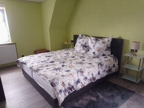 Ein Schlafzimmer mit einem Bett, einem Nachttisch, einer Lampe und einem Heizkörper.