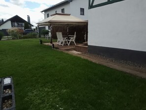A residential property with a covered patio, outdoor seating, and a well-maintained lawn.