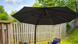 Eine Terrassenausstattung mit Korbmöbeln, einem Tisch und einem großen Sonnenschirm.