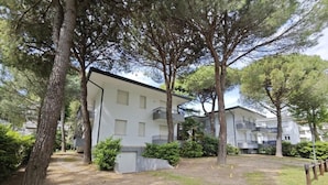 Un edificio residencial con varios balcones, rodeado de árboles y un área verde.