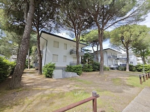 Ein Mehrfamilienhaus mit mehreren Balkonen, umgeben von Bäumen und einer Rasenfläche.