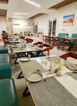 A dining area with multiple tables, chairs, and a buffet setup.