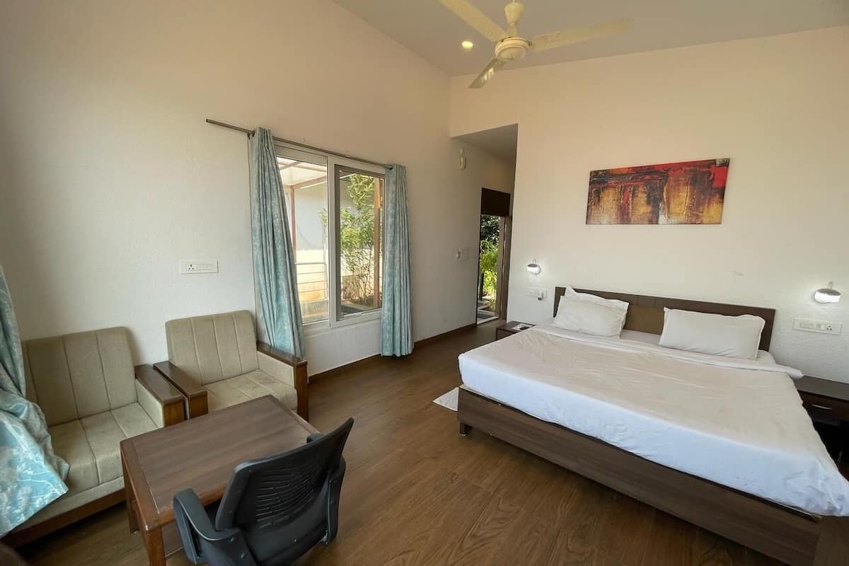 Une chambre dâhĂŽtel avec un lit, un bureau, une chaise, un ventilateur de plafond et un tableau au mur.