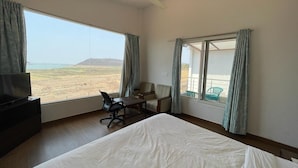 Camera d'albergo con un letto grande, una scrivania con sedia, una televisione e vista sulla spiaggia.