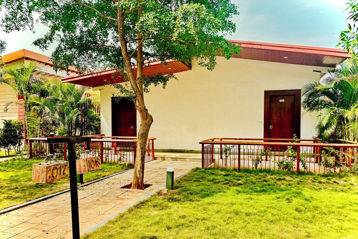 A building with a red roof, a door labeled '1018', and a tree in the foreground.