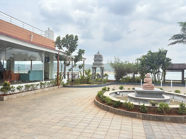 A courtyard with a statue, a gazebo, and a view of the sea.