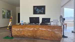 Una reception con due computer, una ventola e un quadro appeso al muro.