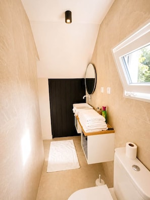 A modern bathroom with a vanity, mirror, towel rack, and toilet.