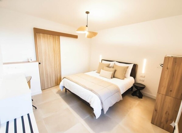 A bedroom with a bed, bedside table, and a wooden wardrobe.