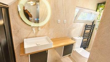 A modern bathroom with a vanity, mirror, and toilet.