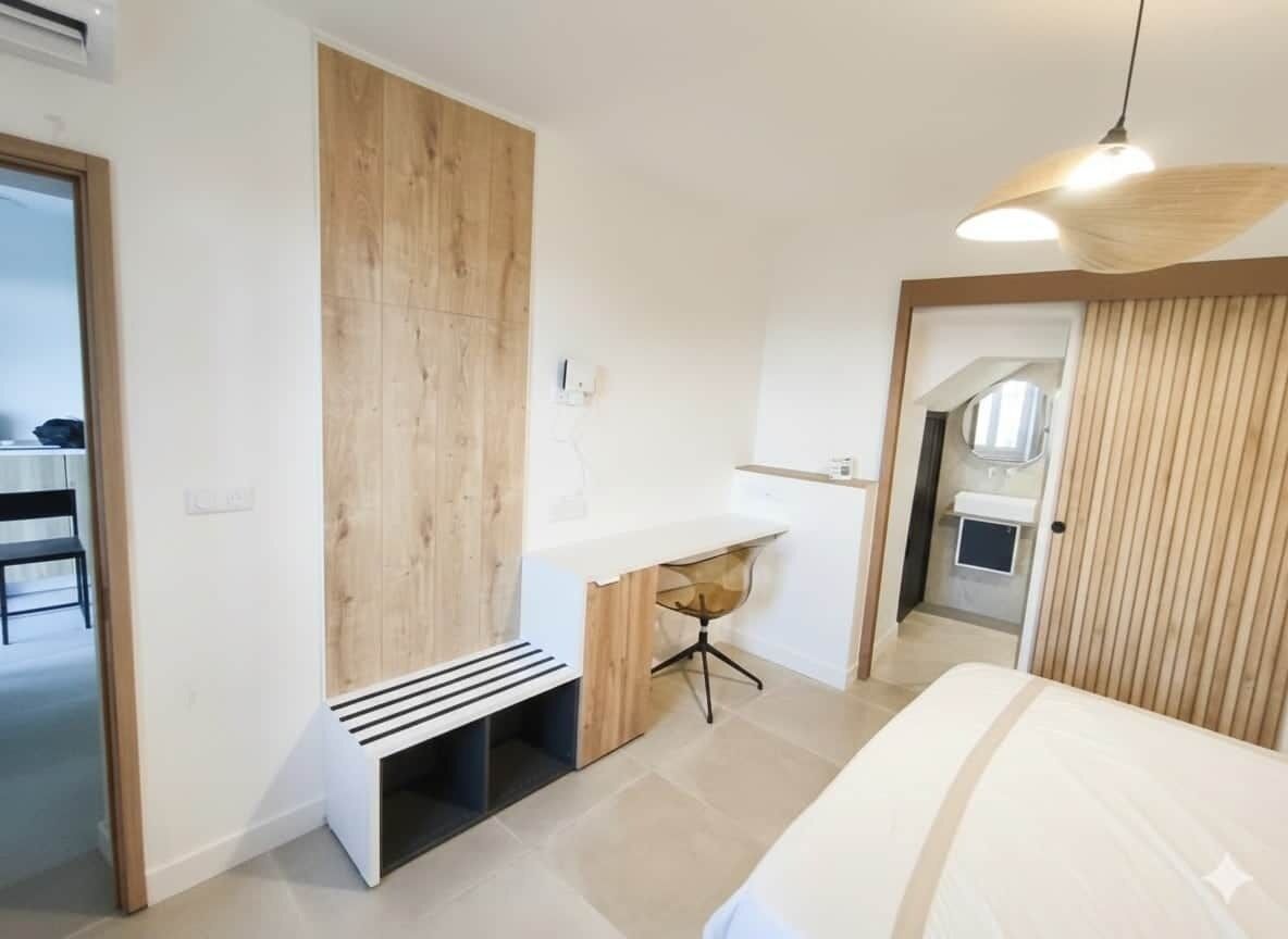 A modern bedroom with a bed, a desk, and a bench.