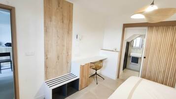 A modern bedroom with a bed, a desk, and a bench.