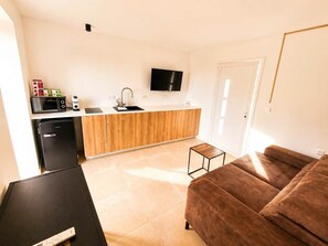 Een moderne keuken met een televisie, een koelkast en een houten aanrecht.