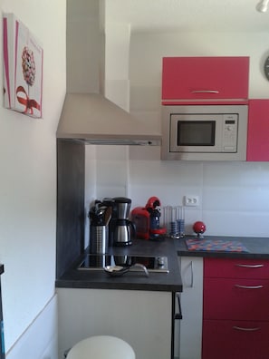 A kitchen with a microwave, coffee maker, and red cabinets. - Comfortable farmhouse for 6 people, private parking, direct access to the beach (Cavalaire-sur-Mer)