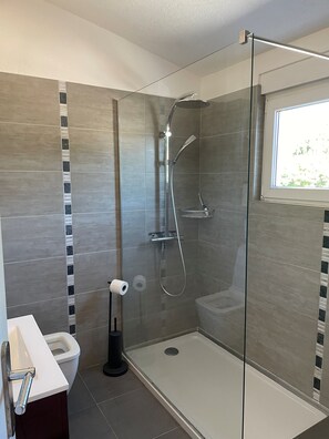 A modern bathroom with a glass-enclosed shower, a toilet, and a sink with a towel rack. - Vrbo Property (Cavalaire-sur-Mer)