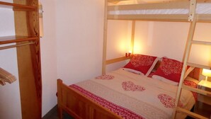 Una cama litera con estructura de madera, una colcha estampada y dos lámparas de noche.