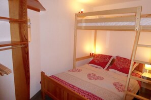 A bunk bed with a wooden frame, a patterned bedspread, and two bedside lamps. - Vrbo Property (Saint-Lary-Soulan)