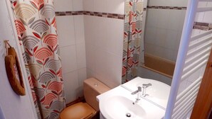 Un baño con inodoro, lavamanos y cortina de ducha.
