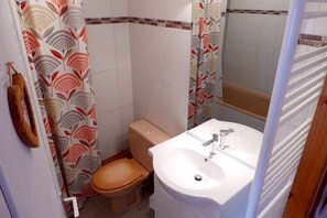 A bathroom with a toilet, sink, and shower curtain. - Vrbo Property (Saint-Lary-Soulan)