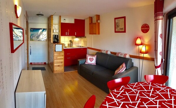 A compact room with a kitchenette, a sofa, a table, and a lamp. - Vrbo Property (Saint-Lary-Soulan)