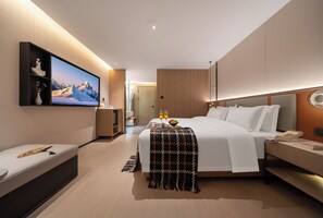 Et moderne hotelværelse med en stor seng, et natbord, et fjernsyn og udsigt til et snedækket bjerg.