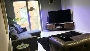 Ein Wohnzimmer mit einer Couch, einem Fernseher und einem kleinen Beistelltisch.