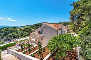Una villa moderna con jardín escalonado, piscina y vistas del paisaje circundante.