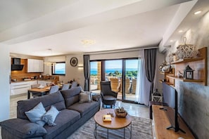 A modern living room with a sofa, coffee table, and a view of the sea. - Villa Kadena (Selca, Brač)