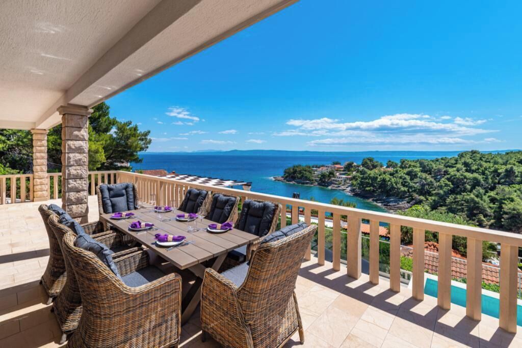 A covered outdoor dining area with wicker furniture and a view of the sea.