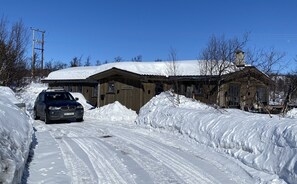 Una carretera cubierta de nieve con un coche estacionado frente a un edificio de madera con un cartel que dice 'Svingen'.