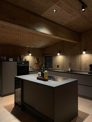 Eine moderne Küche mit Holzvertäfelung, einer zentralen Kochinsel und integrierten Geräten.