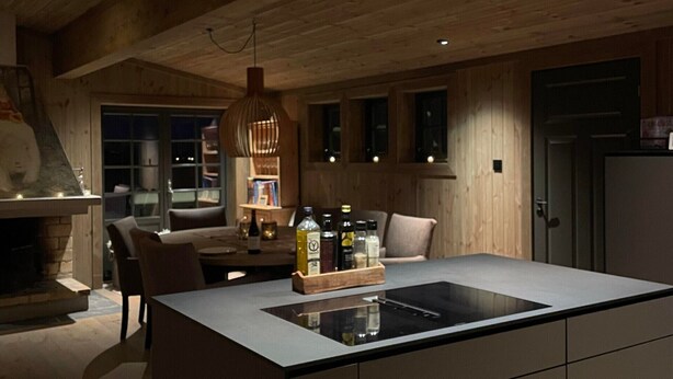Een moderne keuken met een centraal eiland, houten plafond en hanglampen.