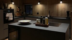 Een moderne keuken met houten lambrisering, een centraal eiland en hanglampen.