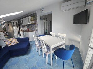 Un espace de vie compact comprenant un coin repas, une kitchenette et un canapé.