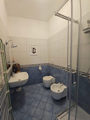 Une salle de bain avec une douche, deux lavabos, des toilettes et un bidet.
