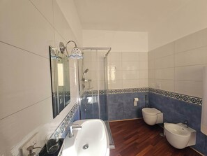 Une salle de bain équipée d’une baignoire, de toilettes et d’un bidet.