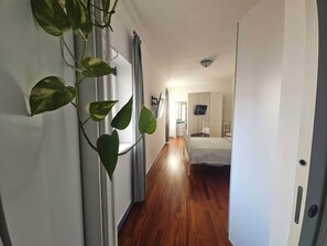 Un couloir comprenant un lit, un téléviseur et une plante.
