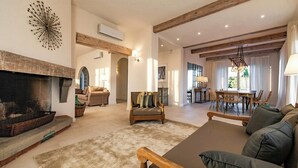 A spacious living area with a fireplace, wooden beams, a dining area, and a sofa. - Historic villa with private pool near Florence (Vinci)