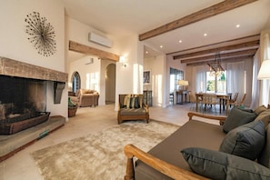 A spacious living area with a fireplace, wooden beams, a dining area, and a sofa. - Historic villa with private pool near Florence (Vinci)