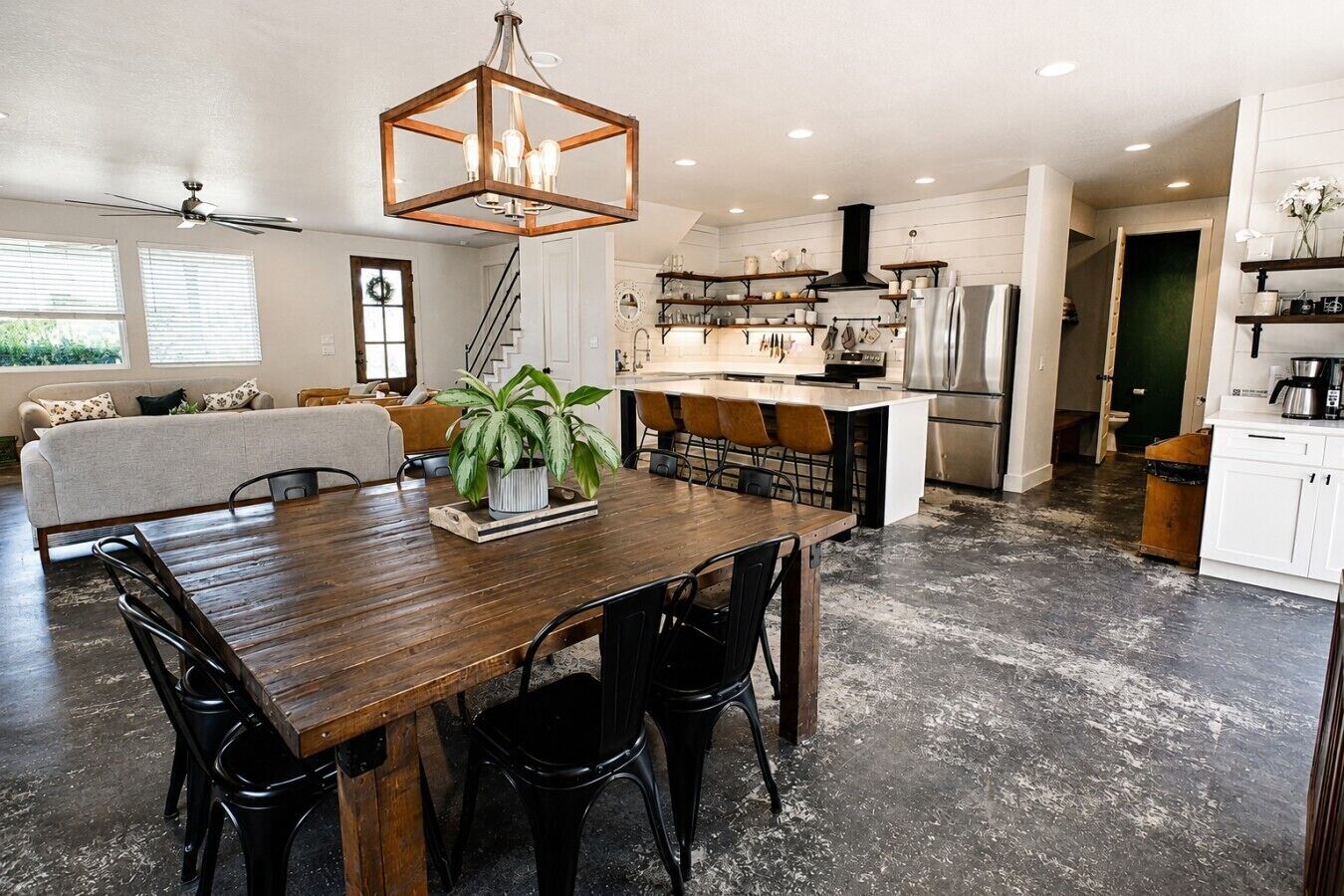A spacious kitchen with a wooden dining table, black chairs, and a hanging light fixture.