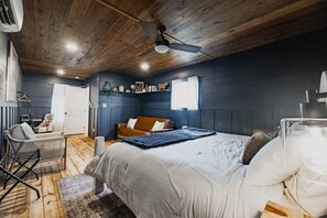 Un dormitorio con cama, una silla, un sofá, un ventilador de techo y un radiador.