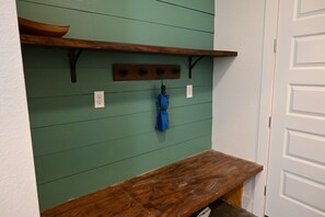 A green wall with a wooden shelf, a blue towel hanging, and a white door. - 3 Houses a Farm Sleeps 20, Swimming Hole, Pools, Hot Tubs, Views (Spring Branch)