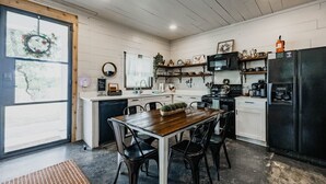 Et køkken med et træbord, sorte stole, et sort køleskab og en mikrobølgeovn.