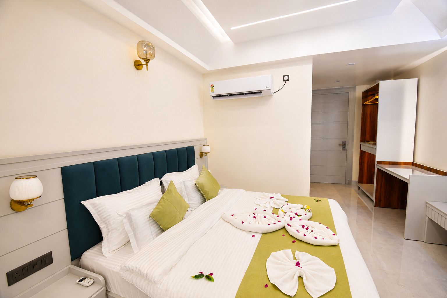 Habitación de hotel con cama, mesita de noche, aire acondicionado instalado en la pared y baño visible a través de una puerta abierta.