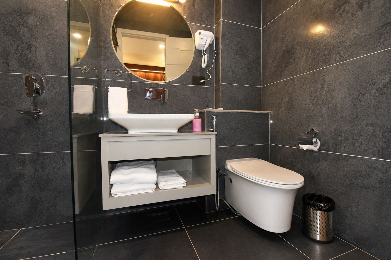 Un bagno moderno con un lavandino bianco, un water, uno specchio e un asciugacapelli.