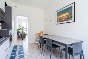 Eine moderne Küche mit Essbereich, einem großen Gemälde und Blick in das Wohnzimmer.