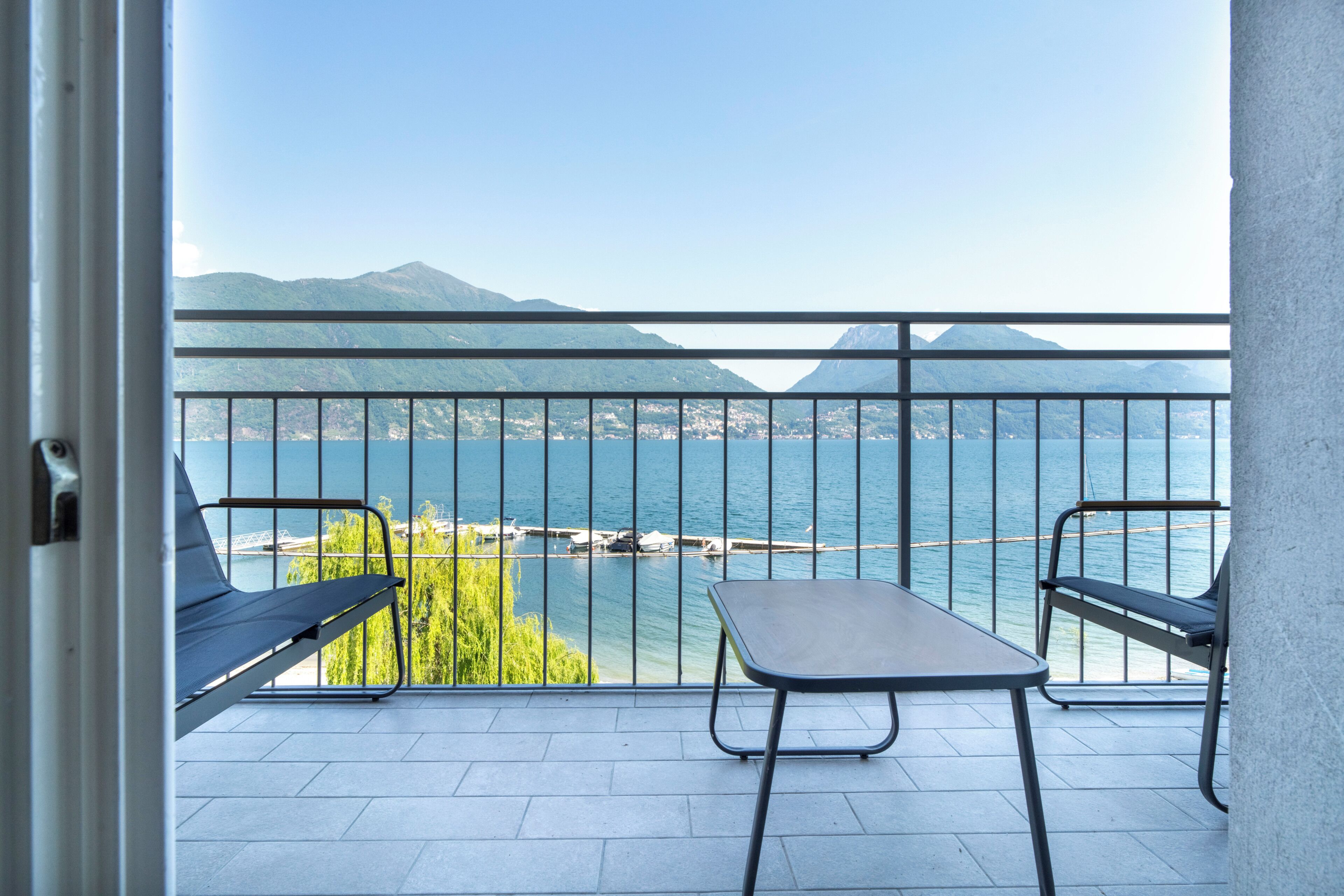 Ein Balkon mit Blick auf einen See, zwei Stühle und ein Tisch.
