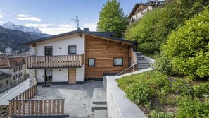 En moderne bygning i to etager med facade i træ, balkon og trappe op til øvre etage.