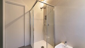 Ein modernes Badezimmer mit einer gläsernen Dusche, einem weißen Waschbecken und einer Tür.