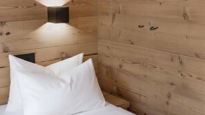 Eine Holzwand mit einer Leuchte und einem Bett mit weißen Kissen.